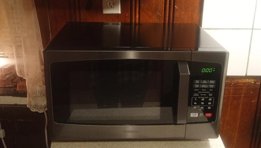 A Toshiba EM925A5A-BS countertop microwave oven placed on a kitchen counter, ready for use in a product review.