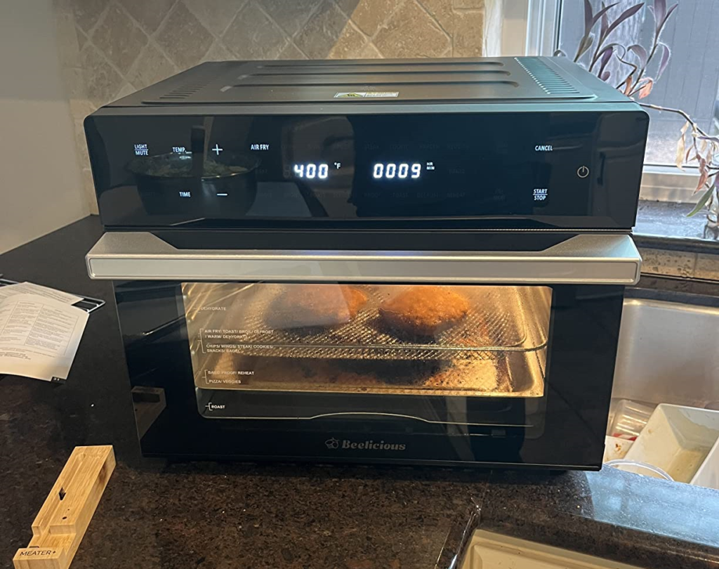 A black Beelicious 32QT Extra Large Air Fryer with a digital display, shown in use for a product review.